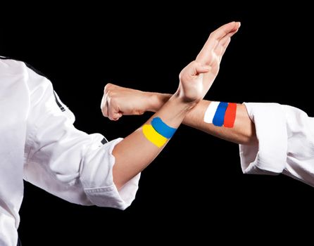 Self defense Ukraine and Russia two fighting hands of representatives of different countries. Hold hands of two fighting people isolated on black background.