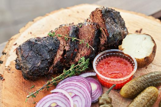 Fresh prepared meat with rosemary potatoe onion and red sauce on a wooden plate