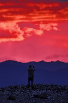 Incredible purple sunset in the mountains. colors of nature. Sunset panorama on the background of mountains. Tourist takes pictures of the landscape on a smartphone