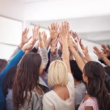 Shot of a business team raising their hands while standing in a huddle.