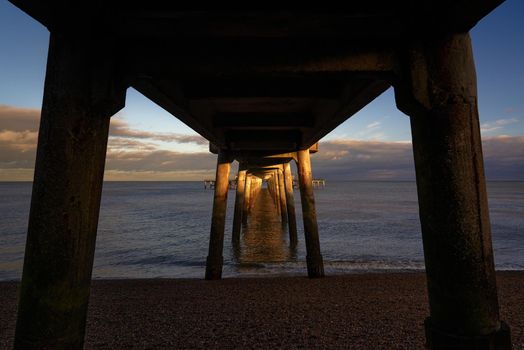 Early evening sun illuminates the piles of Deal Pier in Kent.