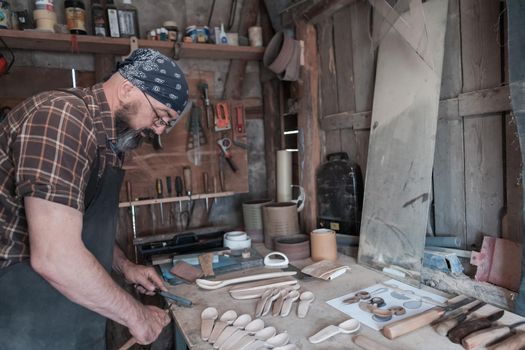 Spoon master in his workshop with wooden products and tools. High quality photo