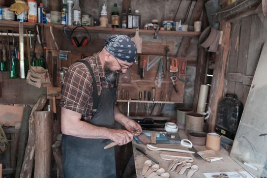 Spoon master in his workshop with wooden products and tools. High quality photo