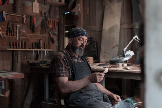 Spoon master in his workshop with wooden products and tools. High quality photo