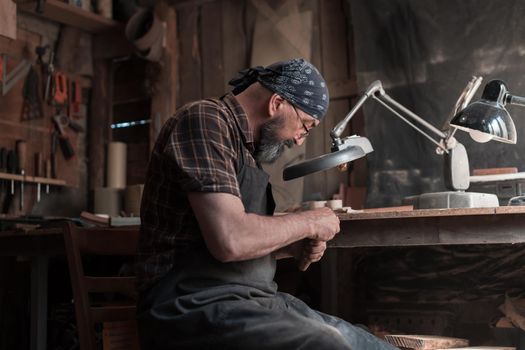 Spoon master in his workshop with wooden products and tools. High quality photo