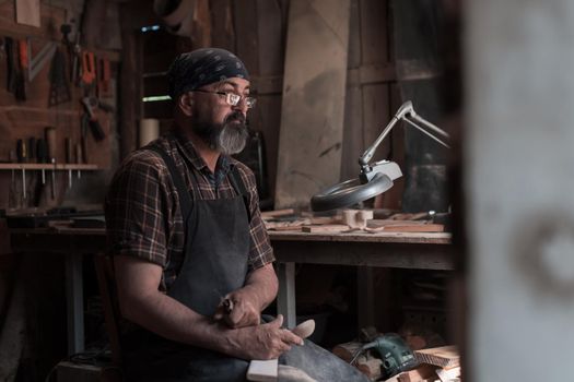 Spoon master in his workshop with wooden products and tools. High quality photo