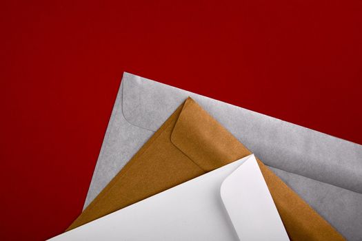 Photo of blank envelopes on a red background. Template for branding identity. Envelopes mockup. White paper isolated on red. Top view.