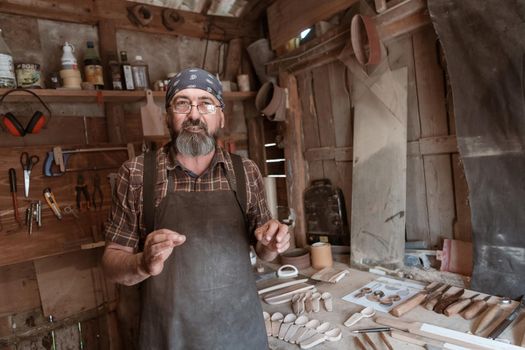 Spoon master in his workshop with wooden products and tools. High quality photo