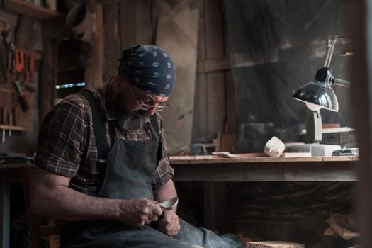 Spoon master in his workshop with wooden products and tools. High quality photo