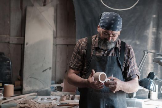 Spoon master in his workshop with wooden products and tools. High quality photo