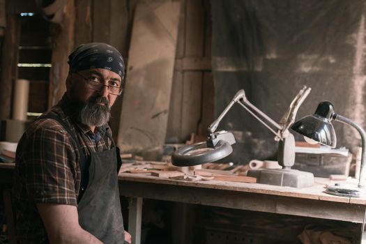 Spoon master in his workshop with wooden products and tools. High quality photo