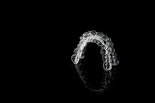 Invisible orthodontics cosmetic brackets on black background, tooth aligners, plastic braces. Modern teeth retainers created on a 3d printer. A way to have a beautiful smile and white teeth.
