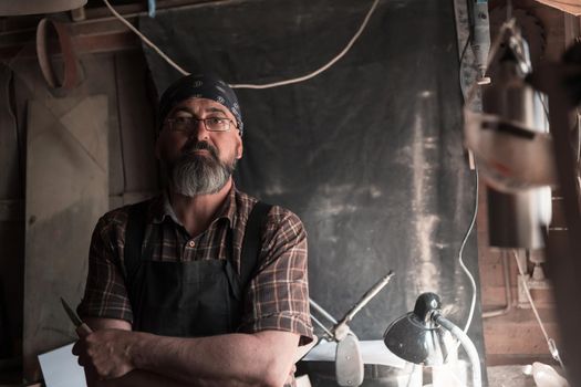 Spoon craft master in his workshop with handmade wooden products and tools. High quality photo