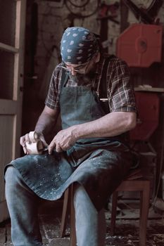 Spoon craft master in his workshop with handmade wooden products and tools working. High quality photo