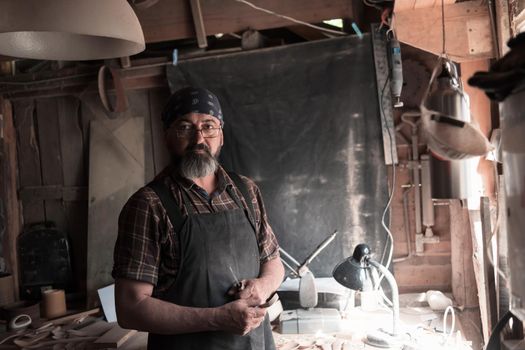 Spoon craft master in his workshop with handmade wooden products and tools. High quality photo