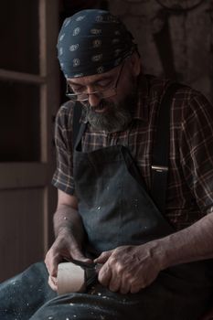 Spoon craft master in his workshop with handmade wooden products and tools working. High quality photo