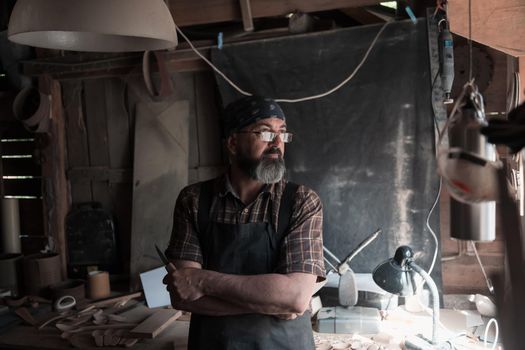 Spoon craft master in his workshop with handmade wooden products and tools. High quality photo