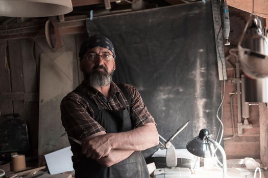 Spoon craft master in his workshop with handmade wooden products and tools. High quality photo