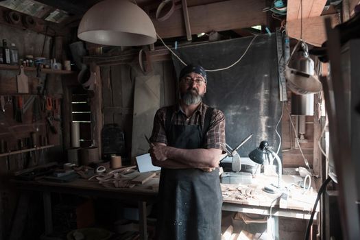 Spoon craft master in his workshop with handmade wooden products and tools. High quality photo