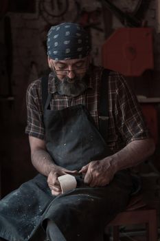 Spoon craft master in his workshop with handmade wooden products and tools working. High quality photo