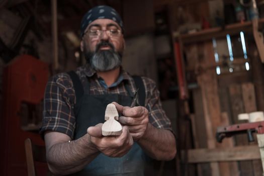 Spoon craft master in his workshop with handmade wooden products and tools working checking curve and line straight. High quality photo