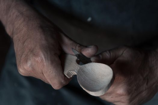Spoon craft master in his workshop with handmade wooden products and tools working checking curve and line straight. High quality photo