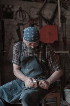 Spoon craft master in his workshop with handmade wooden products and tools working. High quality photo