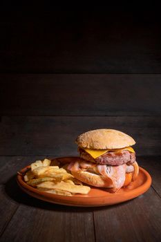 Premium grilled beef hamburger with bacon, cheese and French fries. Delicious American burger on wooden background. High quality photography