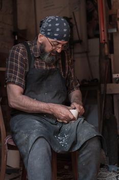 Spoon craft master in his workshop with handmade wooden products and tools working. High quality photo