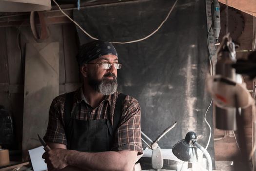 Spoon craft master in his workshop with handmade wooden products and tools. High quality photo