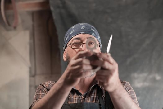 Spoon craft master in his workshop with handmade wooden products and tools working checking curve and line straight. High quality photo