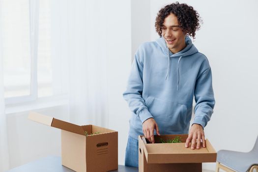 A young man unpacking things from boxes in the room interior. High quality photo