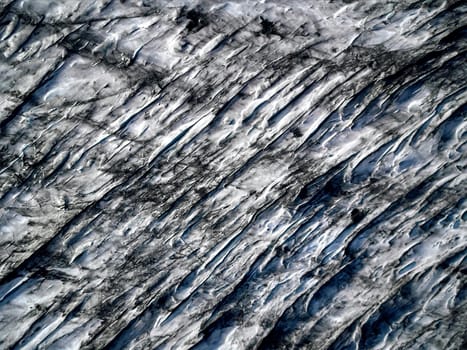 Aerial view of glacier from above, ice and ashes of the volcano texture landscape, beautiful nature ice background from Iceland