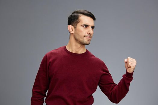 businessman clenching his fist with a serious expression in a red sweater gesturing with hands posing elegant style. High quality photo