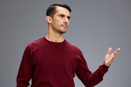 portrait man incredulous look in a red sweater gesturing with hands posing elegant style. High quality photo