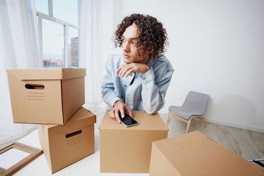 A young man with a phone in hand with boxes moving Lifestyle. High quality photo