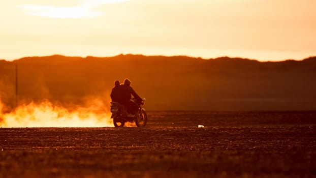 On a motorcycle in the Gobi desert. Dust from under the wheels. Wild Mongolian road.