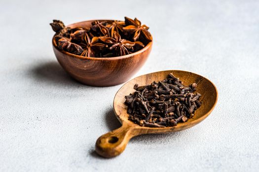 Wooden bowls with organic anise star and cloves on concrete background