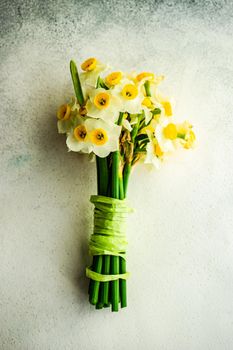 Bouquet of fresh spring daffodil flowers with ribbon on stone background