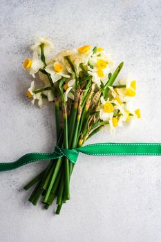 Bouquet of fresh spring daffodil flowers with ribbon on stone background