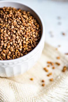 Bowl full of organic raw buckwheat on wooden table with towel