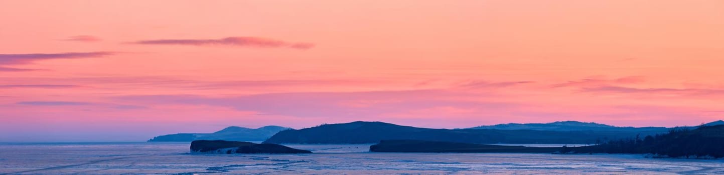 Frozen lake Baikal, at dawn. Winter landscape panorama