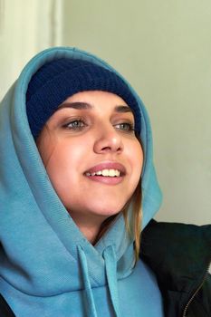Facial portrait of a young beautiful girl in a sweatshirt with a hood. Close up