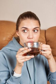 Beautiful brunette with slicked back long hair drinks coffee from a large transparent mug