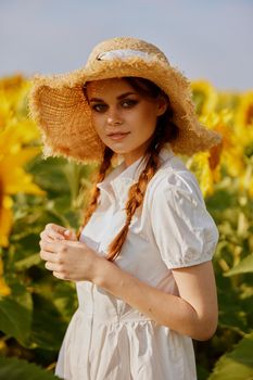 woman with two pigtails in a straw hat in a white dress a field of sunflowers agriculture unaltered. High quality photo