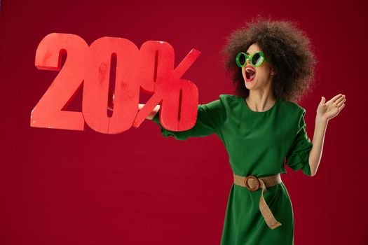 Positive young woman green dress afro hairstyle dark glasses twenty percent in hands studio model unaltered. High quality photo