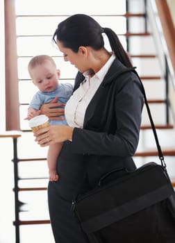 Working mother standing with her briefcase holding a baby.