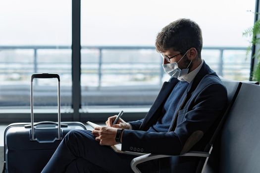 passenger in a protective mask taking notes in his diary. business travel