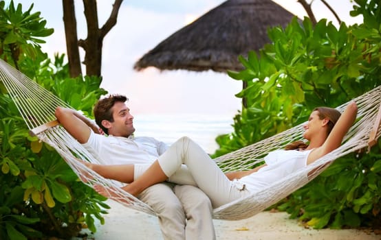 Shot of a happy couple relaxing on a hammock together in their own private paradise - Romance.