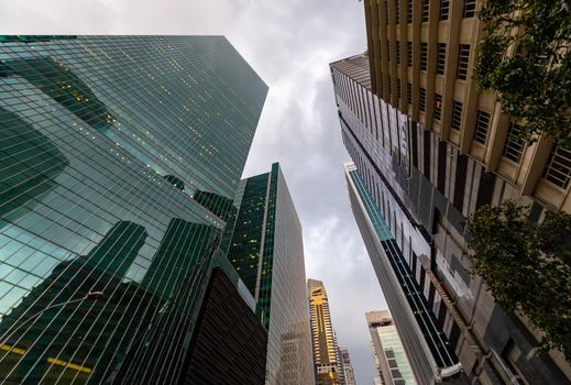 Glass Facades of skyscrapers of the financial district of Singapore on a cloudy evening, bottom view, wide lens, city center, building of large companies without logos. High quality photo